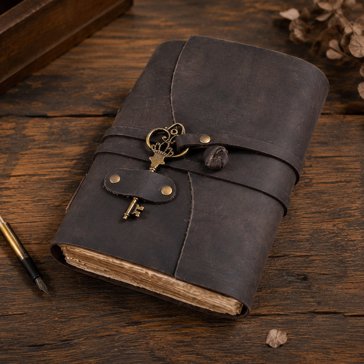 Dark leather journal with antique brass key charm on wooden desk