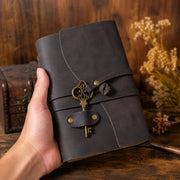 Hand holding dark leather journal showing its size and closure