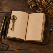 Open leather journal with blank deckle-edge pages and brass key